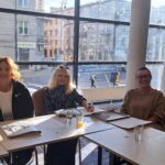 Uśmiechnięte uczestniczki szkolenia siedzą w ławkach, na których leżą materiały szkoleniowe