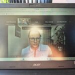 Widok monitora laptopa, na którym otwarta jest aplikacja ZOOM. Widok na szkoleniowca rejestrowany kamerą internetową, który prowadzi wykład szkolenia.